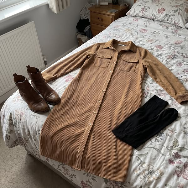 The Averlina ribbed midi dress laid out on a bed with brown ankle boots and black tights