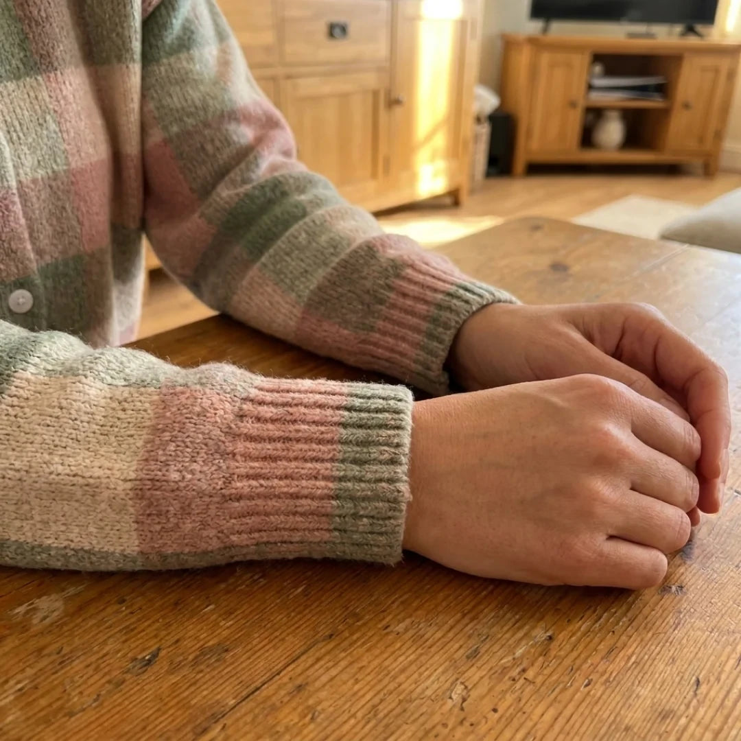 Close-up of the ribbed cuffs of the Grace cardigan on a wooden table