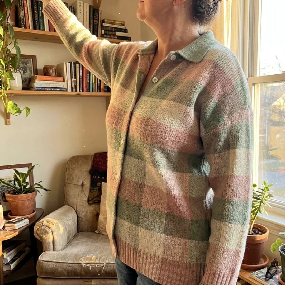 The Grace cardigan worn by a bright window, reaching for a book