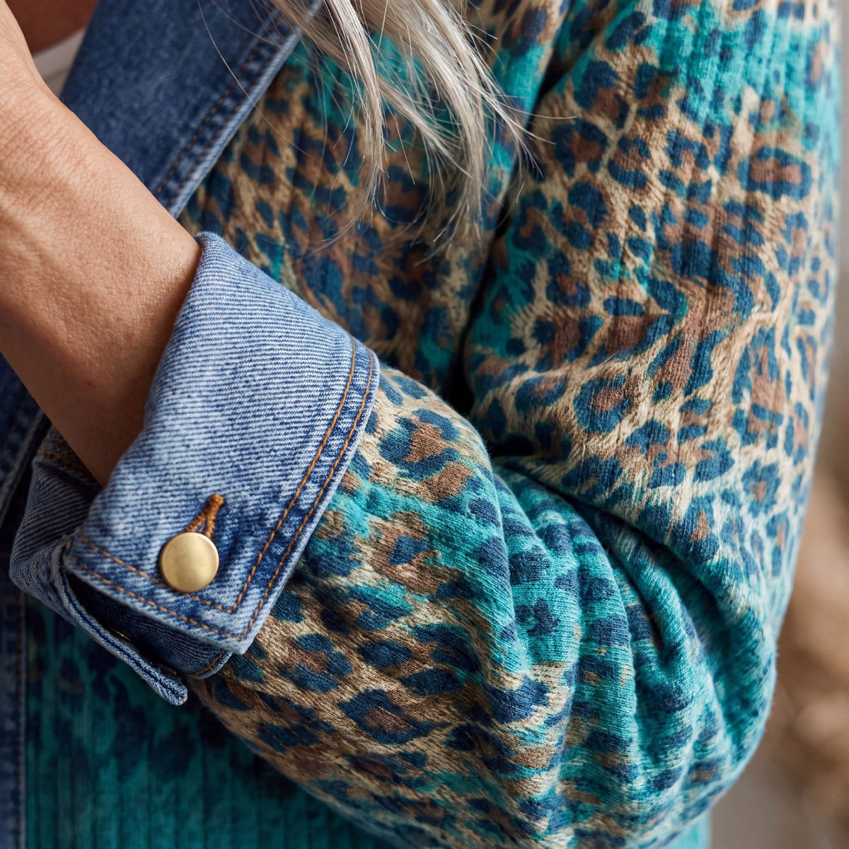 Close-up of the denim-style cuff of the Olivia jacket, turned back, with gold-tone button