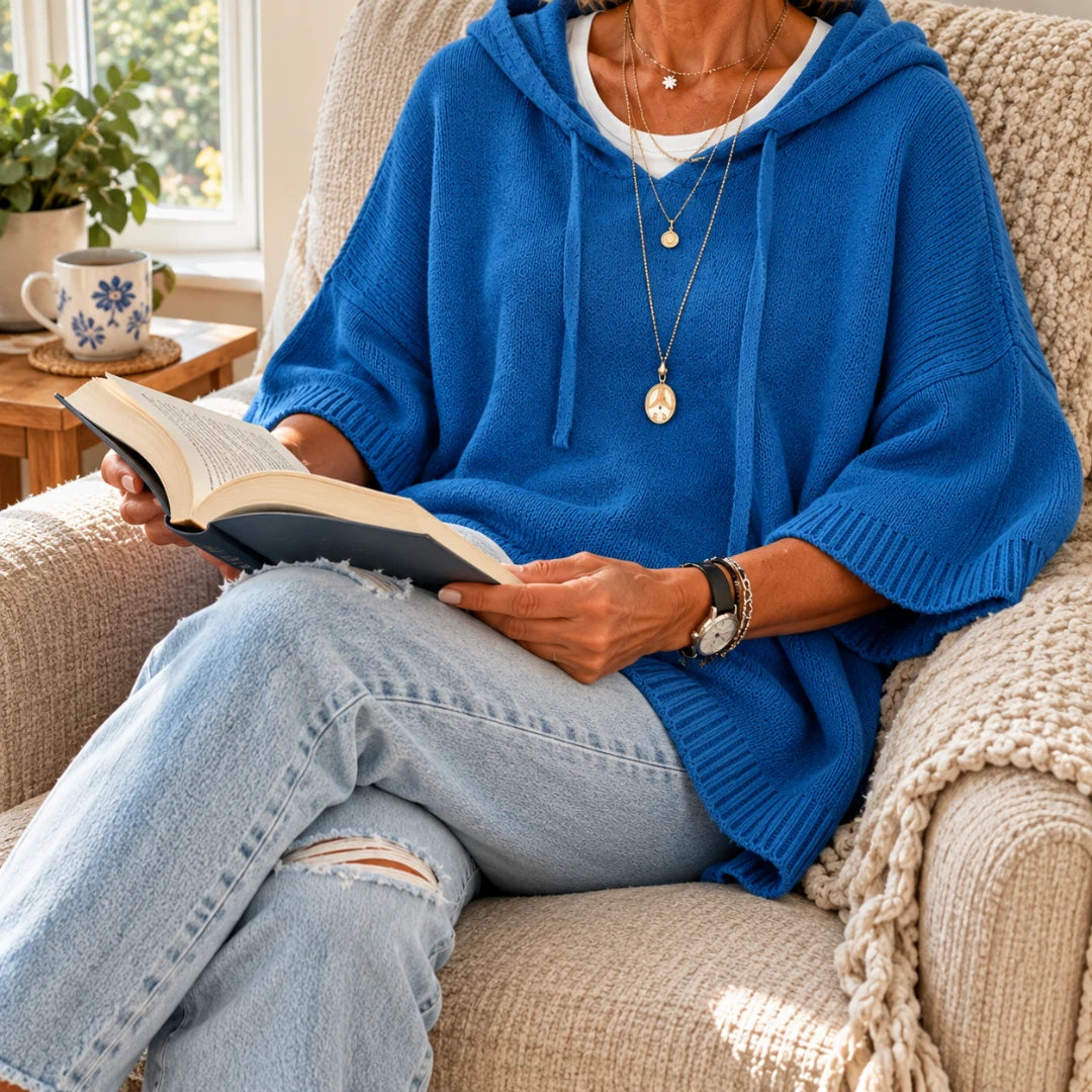 The blue knitted poncho at home with a book