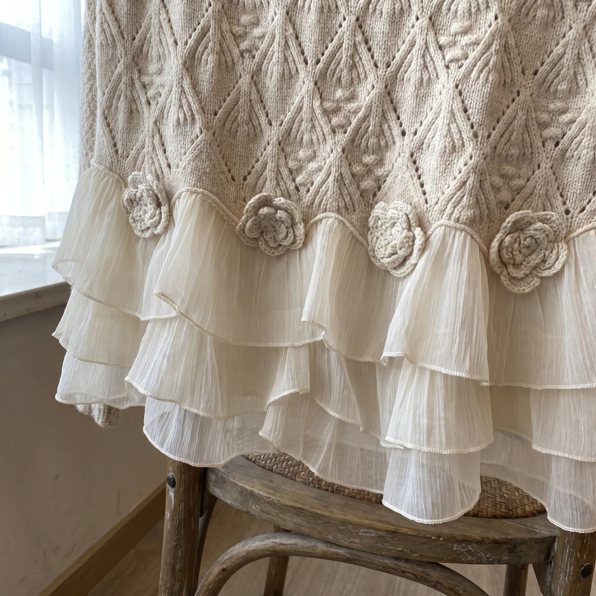 Close-up of the chiffon ruffle hem and crochet flowers of the Ruvella sweater