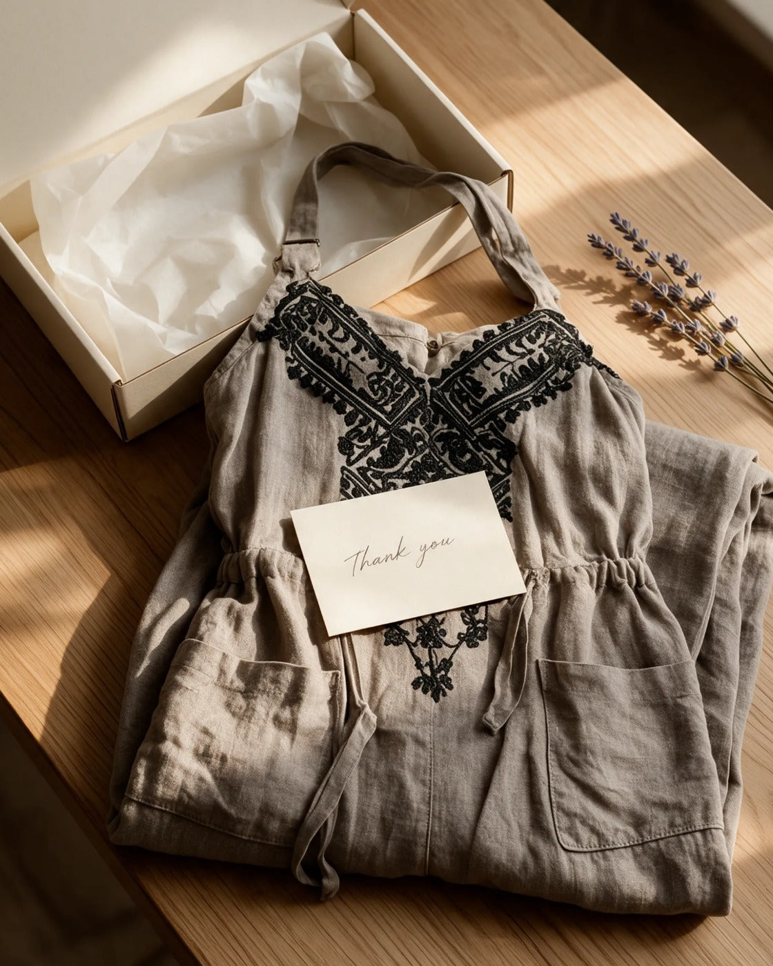The Wren jumpsuit folded beside a cream June & Louise box with tissue paper and a handwritten thank-you card.