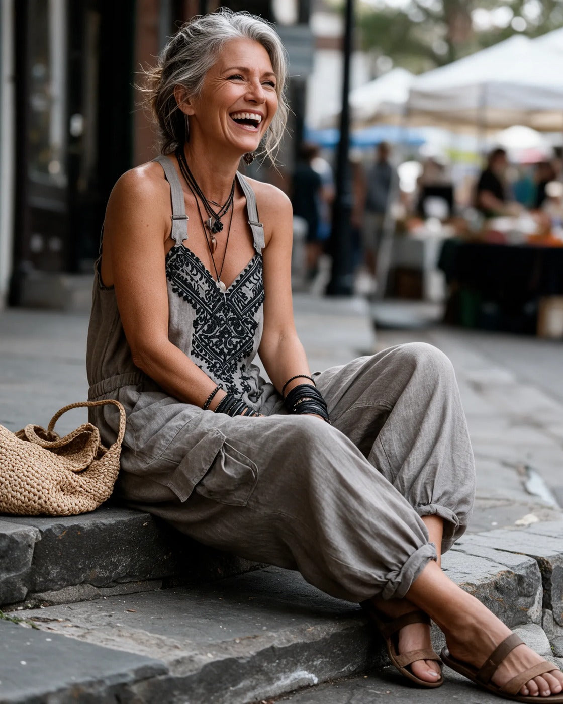 The same woman laughing on the stone steps of a weekend market in Charleston, wearing the Wren with a woven straw bag.