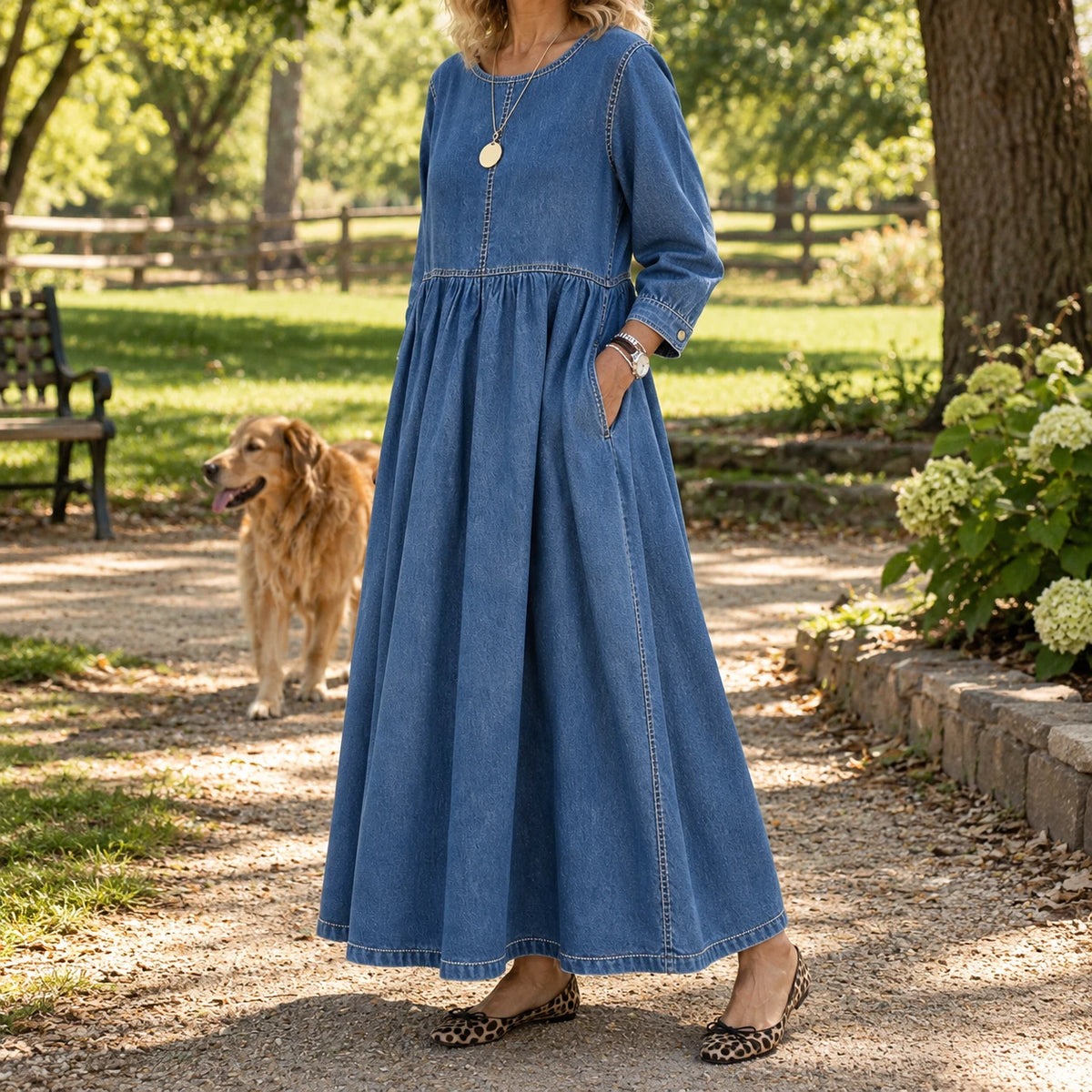 Woman walking her dog in the park in the Zephyrelle denim dress, hands in the pockets, flats on
